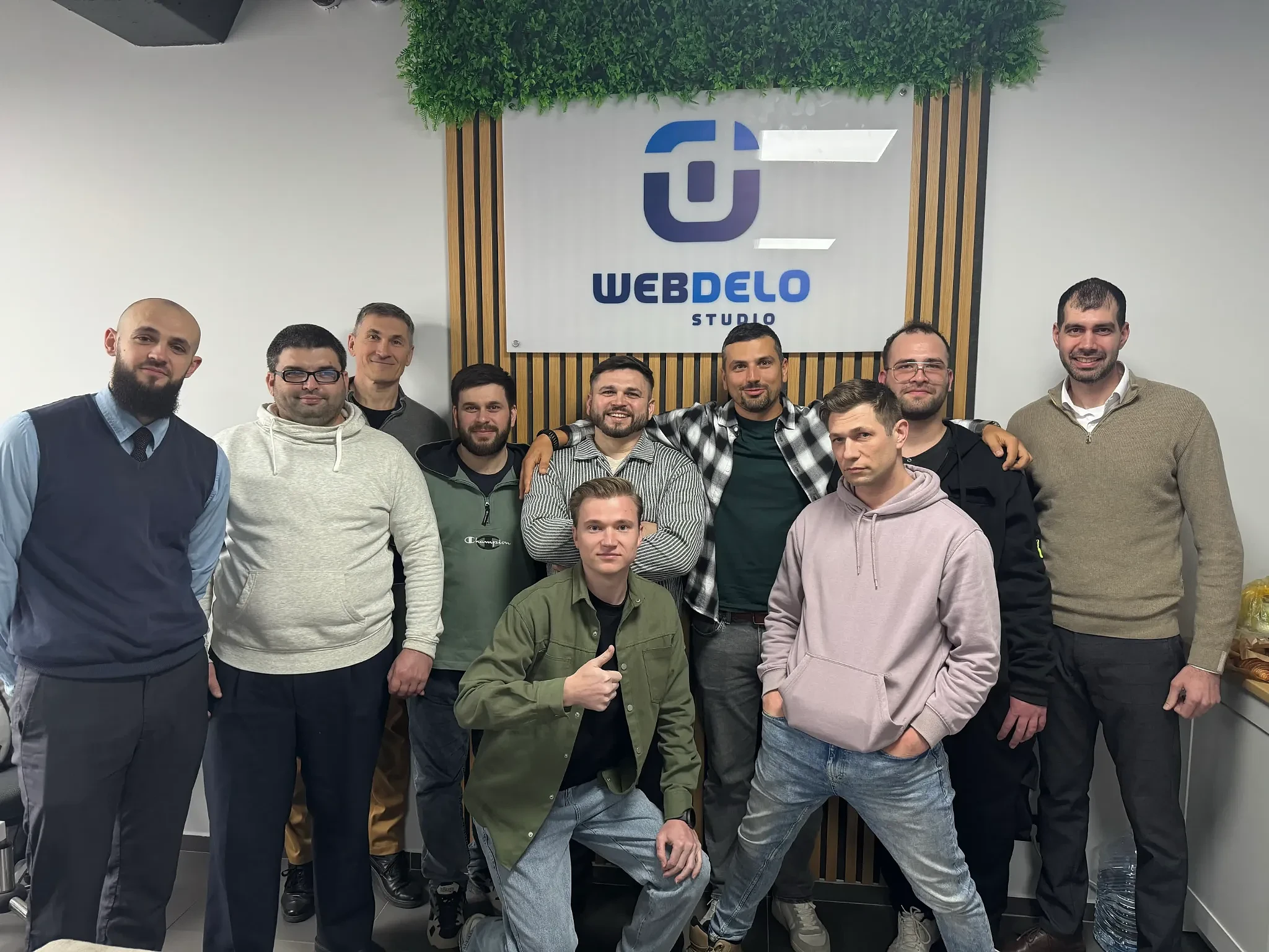 Webdelo SEO team in a group photo by the branded banner.